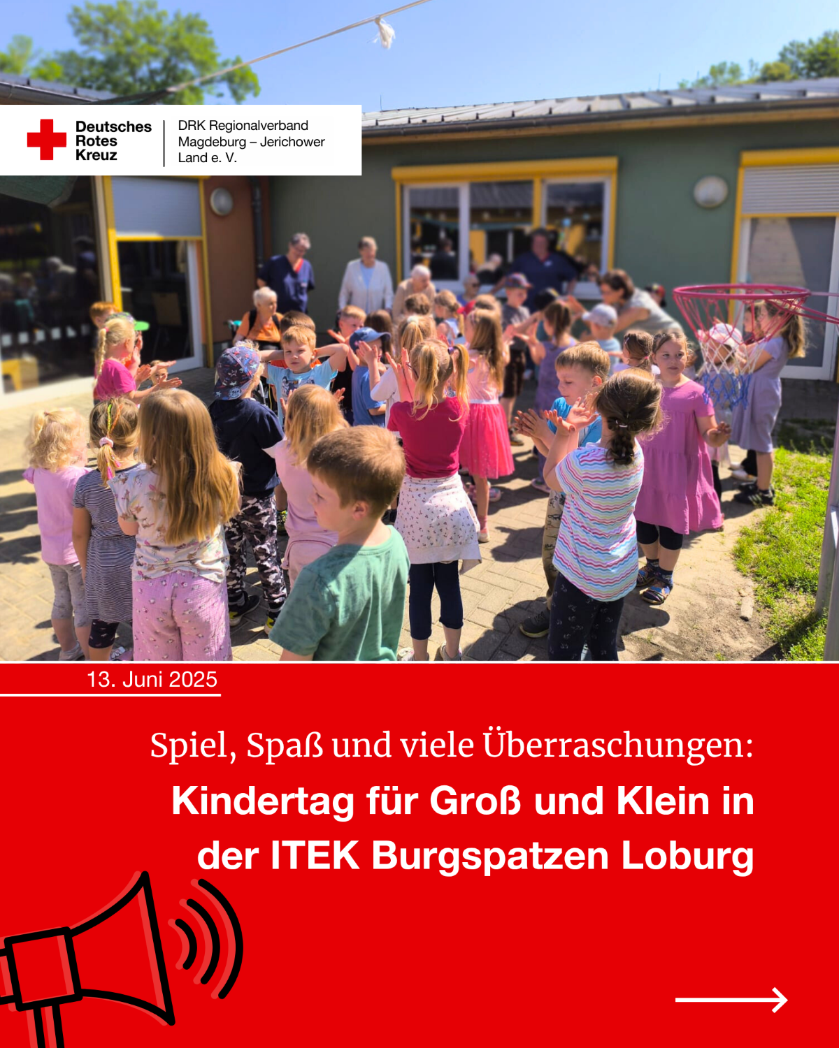 Kinder feiern fröhlich im Außenbereich der DRK-Kita Burgspatzen Loburg zum Kindertag; Erwachsene stehen im Hintergrund, Kinder klatschen und tanzen.