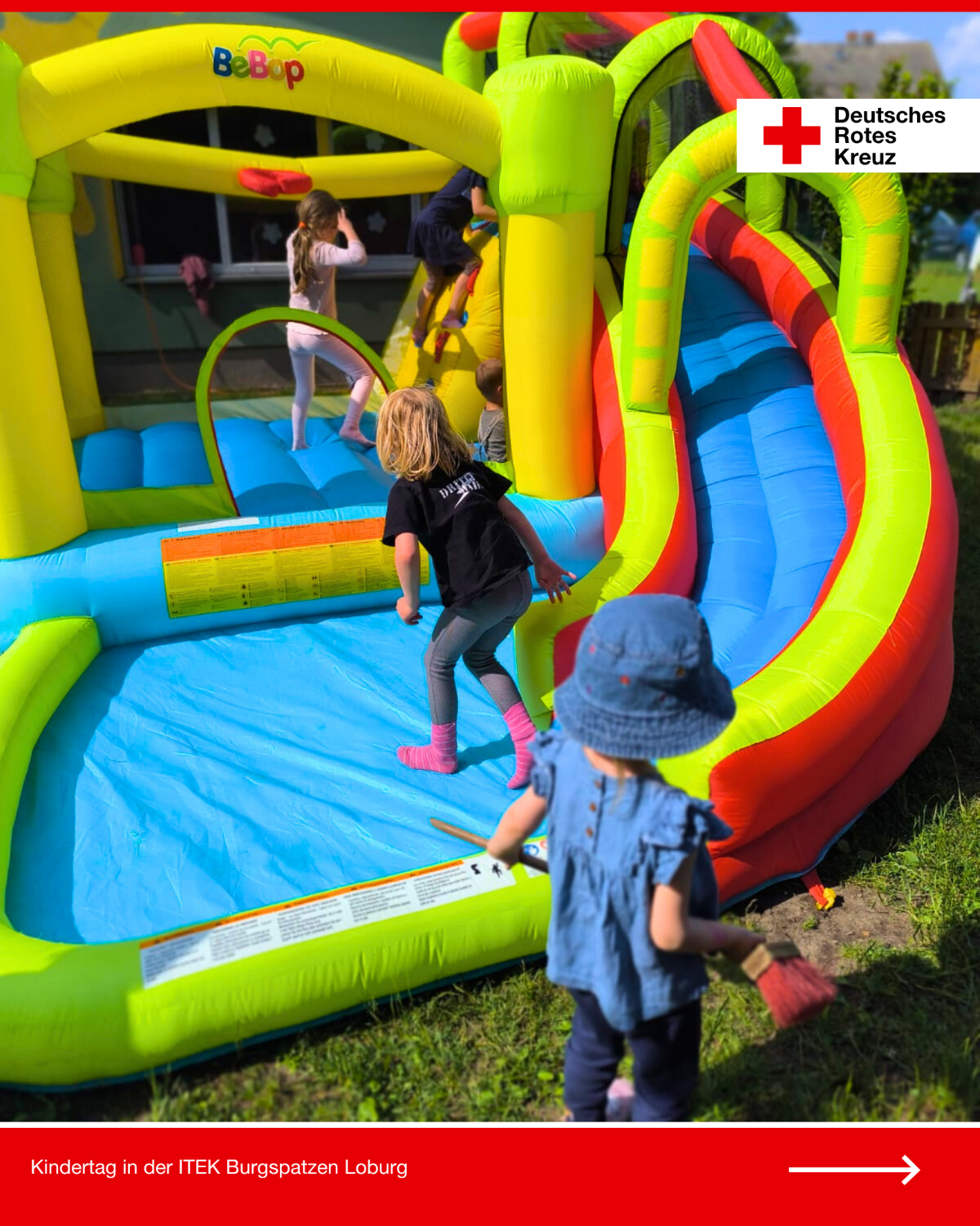 Kinder spielen auf einer bunten Hüpfburg beim DRK-Kindertag in der Kita Burgspatzen Loburg, ein Kleinkind schaut von außen zu.