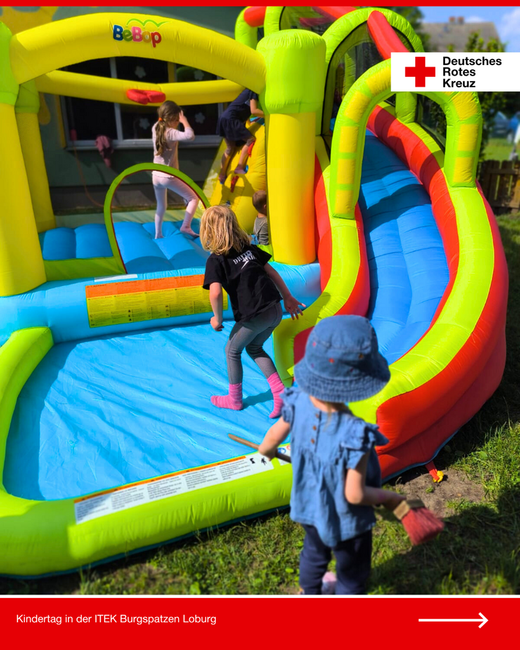 Kinder spielen auf einer bunten Hüpfburg beim DRK-Kindertag in der Kita Burgspatzen Loburg, ein Kleinkind schaut von außen zu.