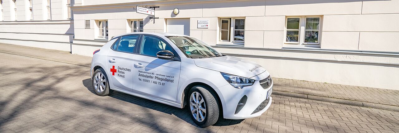 Ein Fahrzeug des DRK-Regionalverbands Magdeburg–Jerichower Land e. V. für den ambulanten Pflegedienst steht vor der Sozialstation Burg in der Berliner Straße 42. Das Auto trägt das DRK-Logo und die Kontaktdaten des Pflegedienstes.