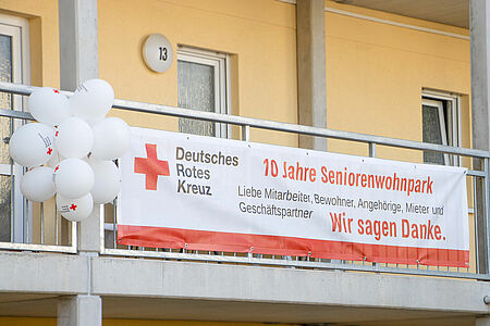 Banner am Balkon des DRK-Seniorenwohnparks Magdeburg mit der Aufschrift „10 Jahre Seniorenwohnpark – Wir sagen Danke“ und weißen Luftballons, aufgenommen am 9. Mai 2024.