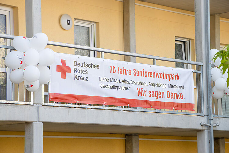Banner am Balkon des DRK-Seniorenwohnparks Magdeburg mit der Aufschrift „10 Jahre Seniorenwohnpark – Wir sagen Danke“ und weißen Luftballons, aufgenommen am 9. Mai 2024.