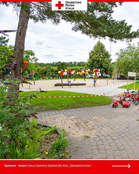 Übersicht über die Spiel-Fahrbahn mit Ballons, Schildern und Sandfläche auf dem Gelände der DRK-Kita „Gänseblümchen“.