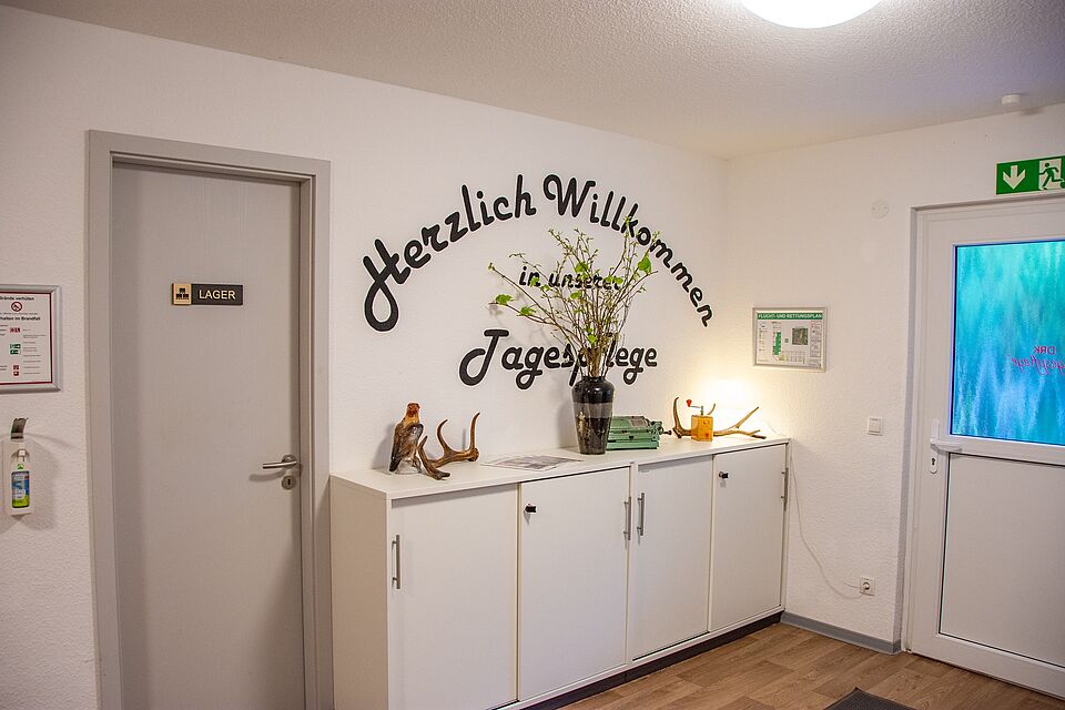 Empfangsbereich der DRK-Tagespflege Möckern mit Willkommensschriftzug an der Wand, Schränken und Dekoration.