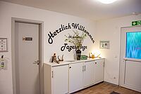 Empfangsbereich der DRK-Tagespflege Möckern mit Willkommensschriftzug an der Wand, Schränken und Dekoration.