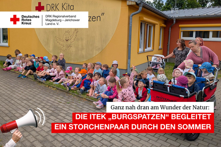 Kindergruppe der DRK-Kita „Burgspatzen“ sitzt vor der gelben Kita-Fassade, einige Kinder im Krippenwagen, oben eingeblendet der Titel „Die ITEK ‚Burgspatzen‘ begleitet ein Storchenpaar durch den Sommer“.