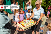 Kinder und Erzieherinnen halten eine große Jubiläumstorte mit der Aufschrift „45 Jahre Kita“.