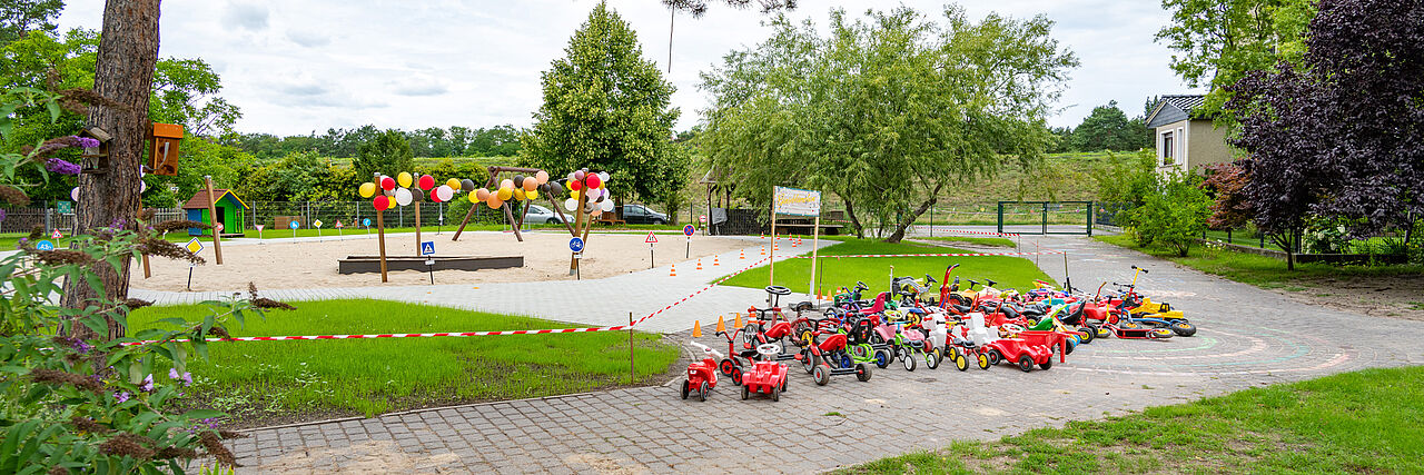 Neue Spiel-Fahrbahn der DRK-Kita „Gänseblümchen“ mit Bobbycars, Verkehrsschildern und bunten Luftballons zur Einweihung.