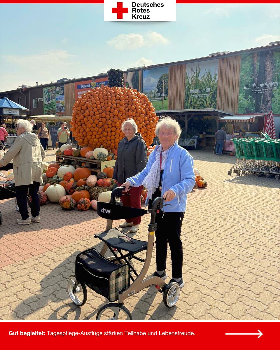 Zwei ältere Damen mit Rollator vor einem großen Kürbis aus kleinen Zierkürbissen auf dem Spargelhof Klaistow.