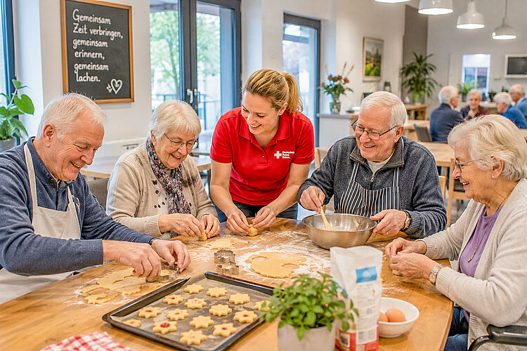Seniorinnen und Senioren backen gemeinsam mit einer Mitarbeiterin Plätzchen in der Tagespflege.