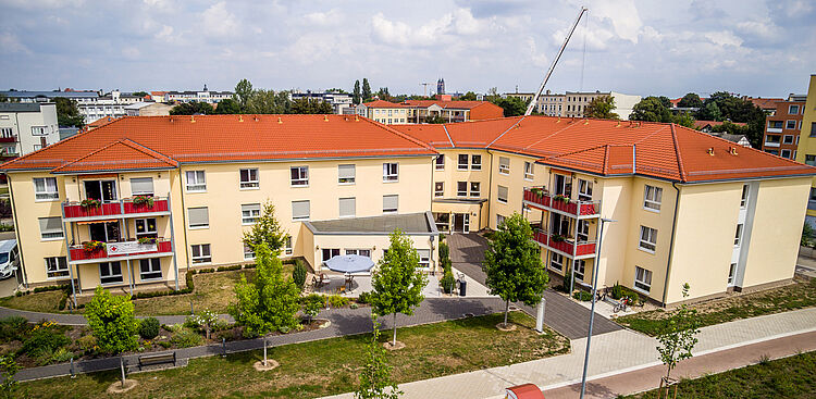 Drohnenaufnahme des DRK-Seniorenwohnparks Magdeburg mit Blick auf den begrünten Innenhof, die Außenfassade mit Balkonen und das rote Dach.