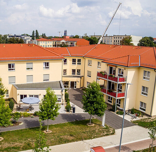 Drohnenaufnahme des DRK-Seniorenwohnparks Magdeburg mit Blick auf den begrünten Innenhof, die Außenfassade mit Balkonen und das rote Dach.