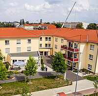 Drohnenaufnahme des DRK-Seniorenwohnparks Magdeburg mit Blick auf den begrünten Innenhof, die Außenfassade mit Balkonen und das rote Dach.