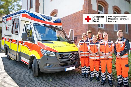 Gruppenfoto der neuen Notfallsanitäter-Azubis vor der Rettungswache Burg mit dem RTW Genthin 83/1, daneben das DRK-Logo.