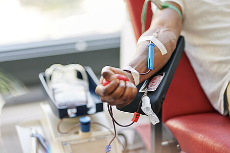 Arm einer Person während der Blutspende beim DRK, im Vordergrund die Blutbeutel und das medizinische Equipment.