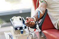 Arm einer Person während der Blutspende beim DRK, im Vordergrund die Blutbeutel und das medizinische Equipment.