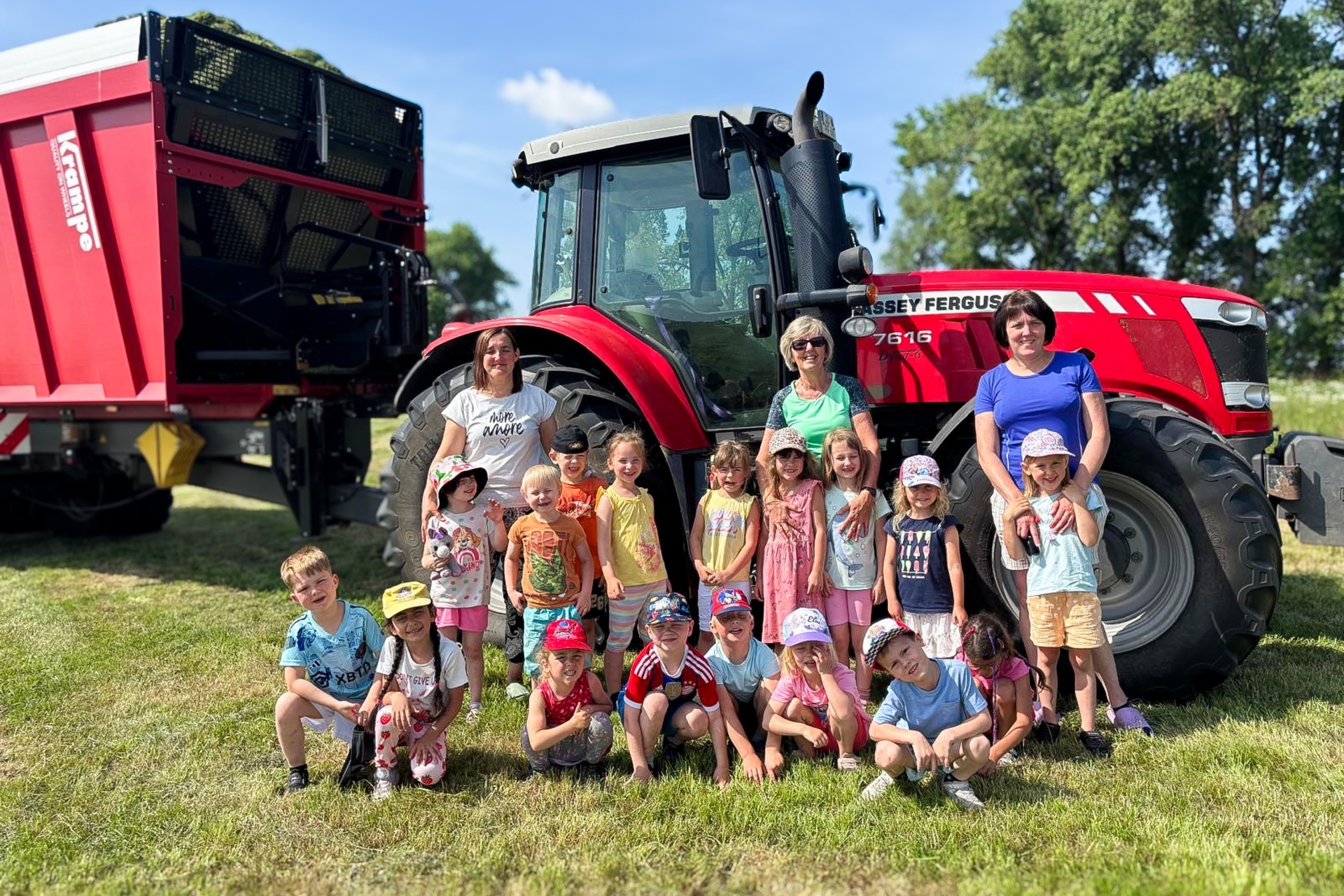 Gruppenfoto von Kindern und Erzieherinnen der DRK-Kita „Rasselbande“ vor einem roten Traktor auf dem Bauernhof in Königsrode.