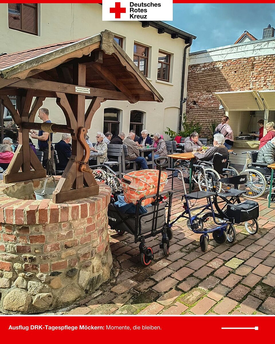 Seniorinnen und Senioren der DRK-Tagespflege Möckern sitzen im Innenhof und genießen ihr Mittagessen.