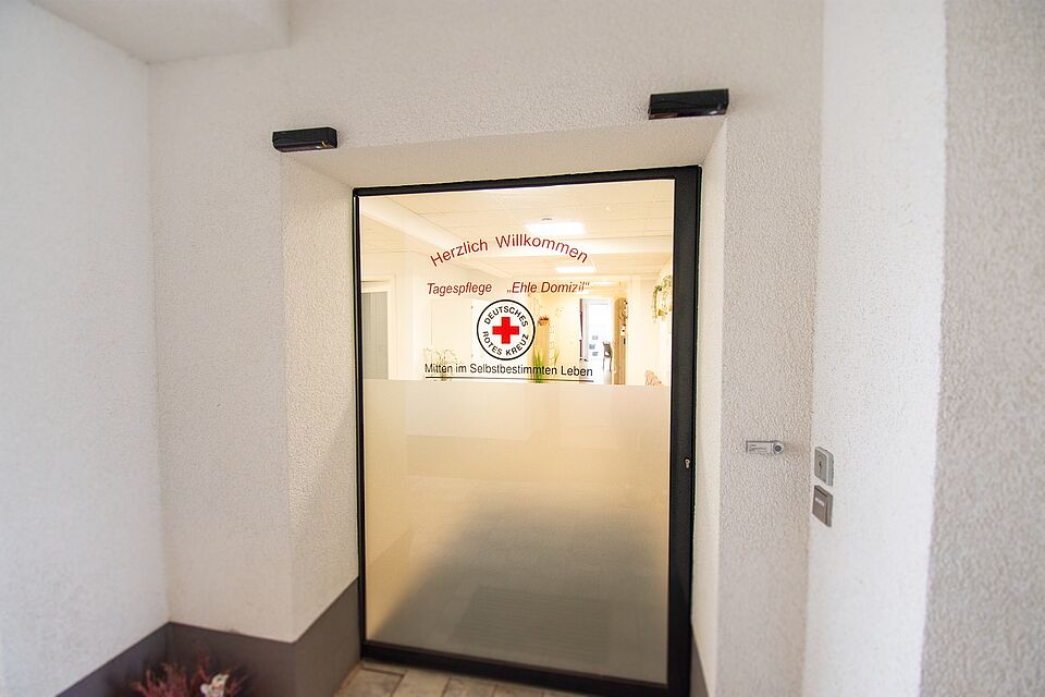 Eingang der DRK-Tagespflege „Ehle Domizil“ mit Glasfront, DRK-Logo und der Aufschrift „Herzlich willkommen“.