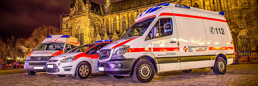 DRK-Rettungsdienstfahrzeuge auf dem Magdeburger Domplatz bei Nacht, drei Fahrzeuge nebeneinander.