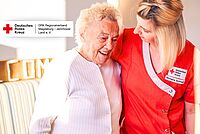 Titelbild zur Stellenausschreibung: Zwei Frauen, eine als DRK-Pflegekraft und eine Seniorin, lachen und gehen Arm in Arm im Seniorenzentrum Möckern.