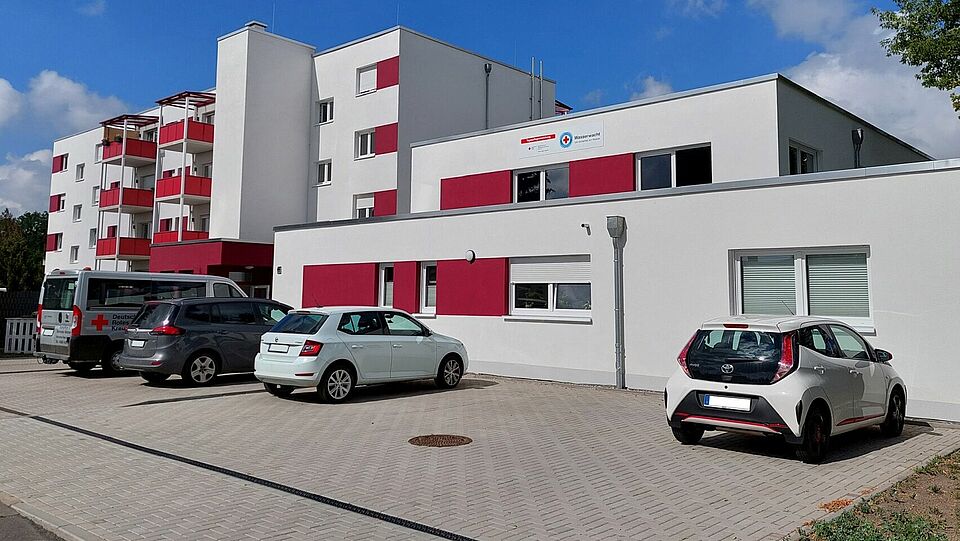 Gebäudeansicht der DRK-Tagespflege „Niegripper Chaussee“ (Siedlung) mit Betreutem Wohnen, Parkplatz im Vordergrund.