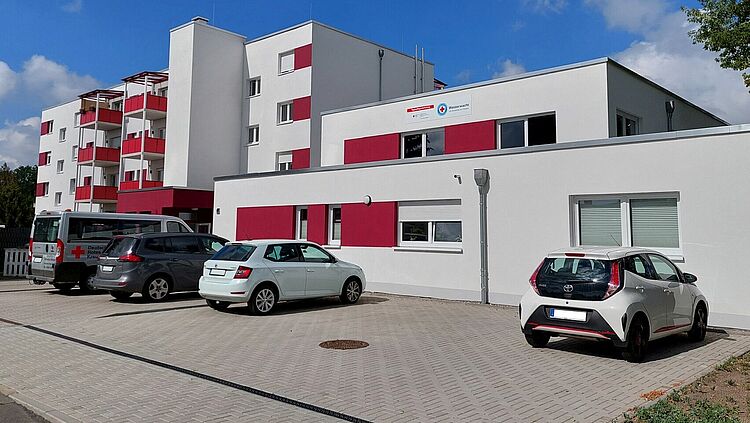 Gebäudeansicht der DRK-Tagespflege „Niegripper Chaussee“ (Siedlung) mit Betreutem Wohnen, Parkplatz im Vordergrund.
