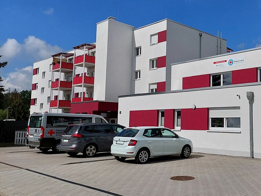 Gebäudeansicht der DRK-Tagespflege „Niegripper Chaussee“ (Siedlung) mit Betreutem Wohnen, Parkplatz im Vordergrund.