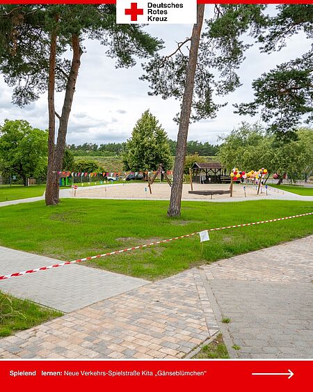 Weitwinkelaufnahme der neuen Spiel-Fahrbahn auf dem Außengelände der DRK-Kita „Gänseblümchen“ – mit Bäumen im Vordergrund und bunten Ballons.